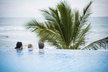 Mother, Father, & Toddler Son Look Out Over the Ocean from a Pool in Mexico