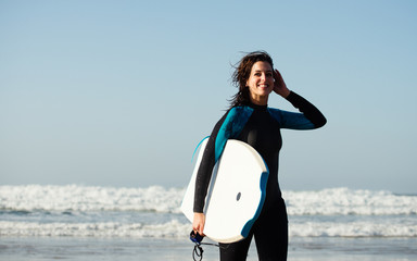 Surfer woman leaving the sea after surfing with bodyboard. Happy woman having fun doing outdoor water sport.