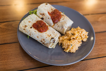 Burrito with Mexican rice served on a plate.