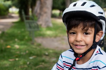 Fototapeta na wymiar Portrait of smiling boy wearing bicycle helmet in park