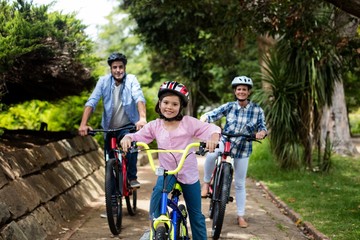 happy parents and daughter standing with bicycle