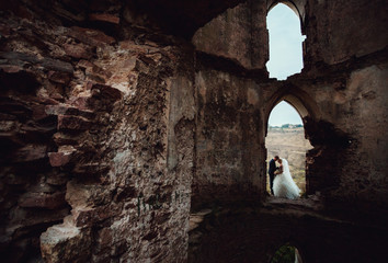 Beautiful stylish newlyweds posing in the ancient ruin