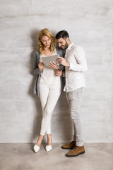 Young couple with tablet by the wall