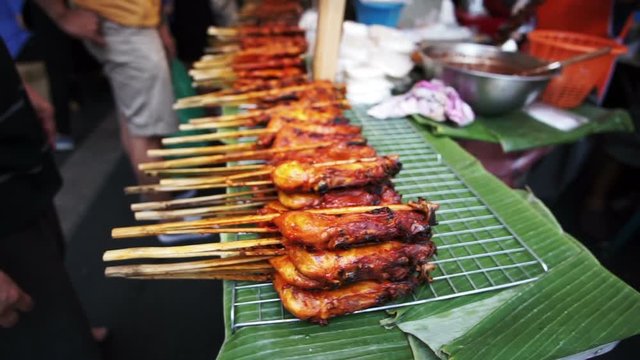 Traditional Thai grilled chicken skewers. Pile of cheap delicious Thai street food selling on banana leaves vendor