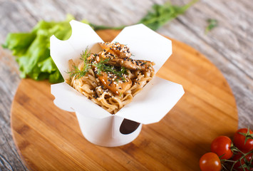 wok noodles with chicken in paper packaging