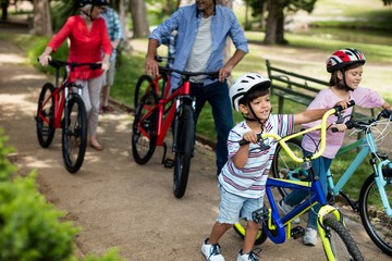 Obraz premium Multi-generation family walking with bicycle in park