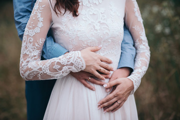 Wedding couple holding hands on nature background.Bride and groom hands with wedding rings