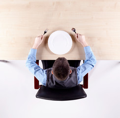 Boy sitting in a chair at the office table with tableware. Top view.