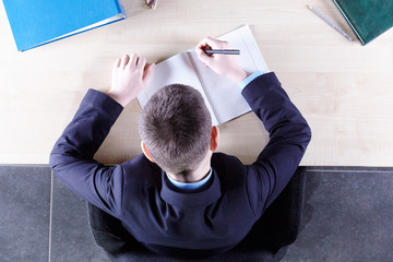 Boy sitting in a chair at the office table. Top view