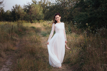 Yong bride spinning in a white dress on the bank on nature.Dress develops in the wind. Happy bride in a wedding dress is spinning.