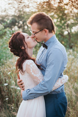 Sunshine portrait of happy bride and groom outdoor in nature location at sunset. Warm summertime