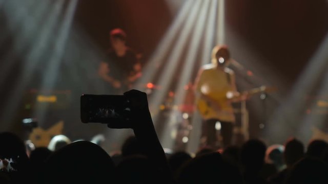 The fan take a photo with guitarist on stage on a rock concert