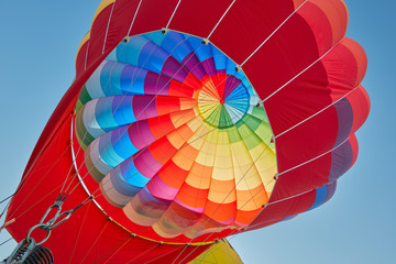 Hot air balloon, colorful aerostat inflating, blue sky