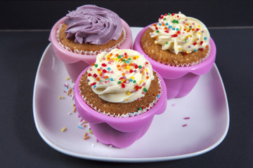 Obraz na płótnie Canvas the cupcakes with white and violet cream on the black background,