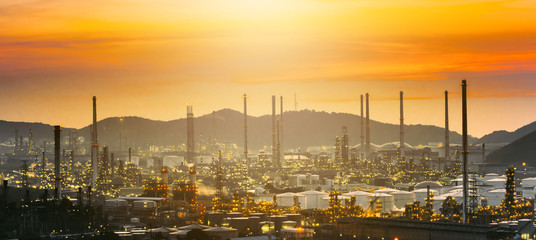 Obraz premium Widok z lotu ptaka noc rafinerii ropy naftowej na tle gór podczas zmierzchu, strefa przemysłowa, elektrownia.