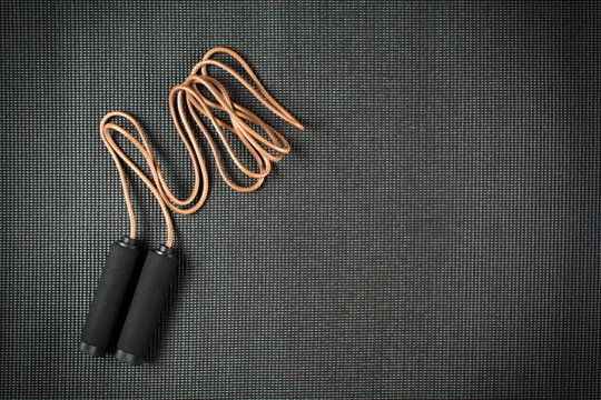 Jump rope on black yoga mat