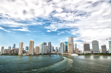 Fototapeta premium Aerial view of Miami skyscrapers with blue cloudy sky, boat sail