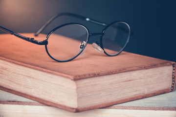 Old books with vintage glasses on a wooden table