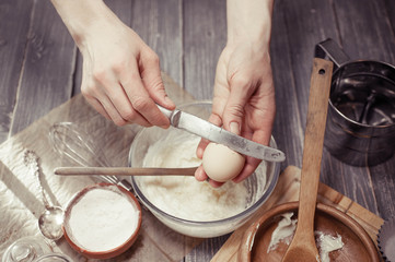 Graceful female hands break eggs in dough for cupcakes. Home-made pastries. Soft toning.