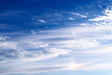 Light cirrus clouds against the blue sky with an element of the solar halo. - obrazy, fototapety, plakaty