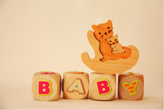 Wort BABY auf Holzw&uuml;rfeln mit Katze und Katzenbaby im Schauckelstuhl auf wei&szlig;em Hintergrund