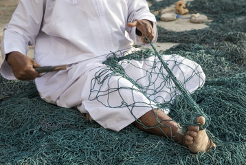 omani man reparing a fish net