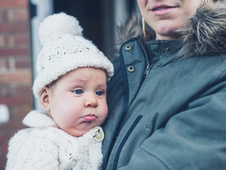 Mother with baby outside house in winter