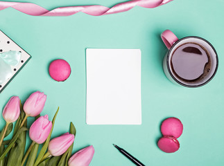 Blank paper, pink tulips, macarons and coffee in a mug