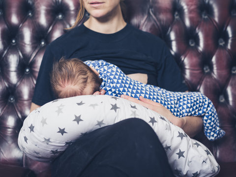 Mother breastfeeding baby on sofa
