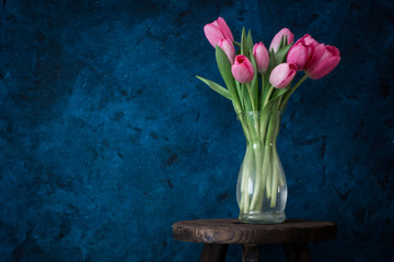 Fresh pink tulip flowers bouquet on shelf in front of swall. View with copy space