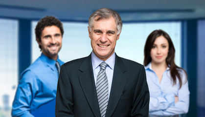 Group of three smiling businesspeople in an office environment