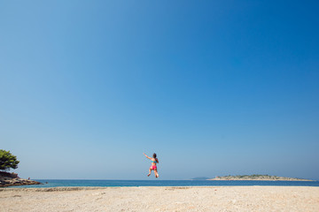 Child little girl is jumping into the sea from a pier