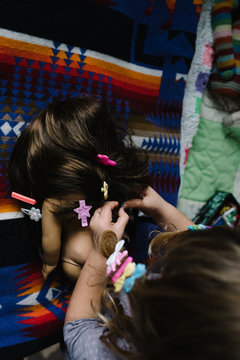Young girl, plaing in bedroom, putting hair clips in doll's hair