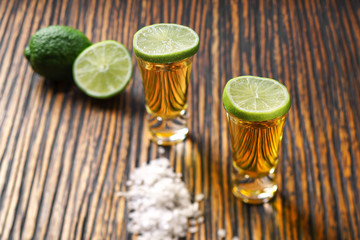 Two shot of gold tequila on a  brown wooden background ,selectiv