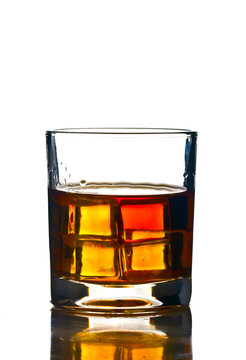glass of whiskey on a white background with symmetrical cubes of ice that glow