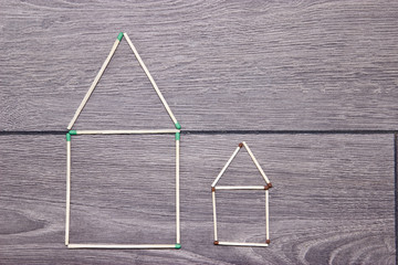 Big and small house made of matches on the floor.