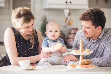 Obraz na płótnie Canvas Happy loving family. Baby boy toddler eat sweet donut in the kitchen.