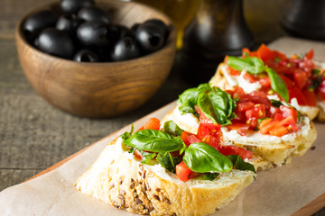 Tomato and cheese fresh made bruschetta. Italian tapas, antipasti with vegetables, herbs and oil on grilled ciabatta and baguette bread.