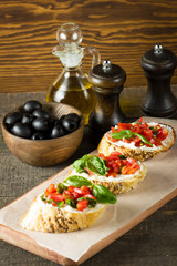 Tomato and cheese fresh made bruschetta. Italian tapas, antipasti with vegetables, herbs and oil on grilled ciabatta and baguette bread.