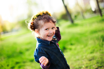 The little girl laughs. Girl running on green grass in the sprin