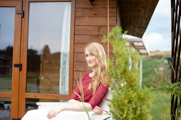 Beautiful bride sitting next to the wooden house