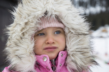 Portrait of little girl dressed in winter clothes with furry hood.