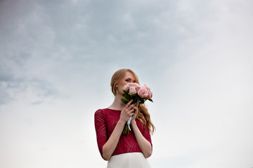 portrait of beautiful blonde bride with bouquet of pink roses