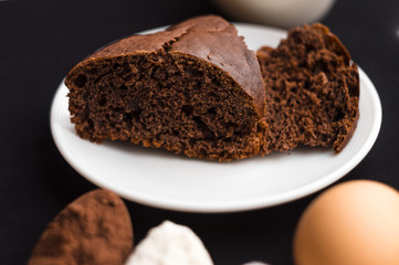 Cake, flour, sugar, cocoa, milk and eggs on a black background. Ingredients for cooking.