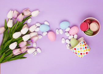 Box, flowers tulips, macaroons and colorful eggs on purple backg