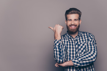 Cheerful toothy bearded stylish man pointing with finger