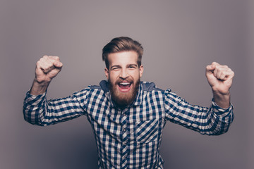 Excited happy young  bearded man triumphing with raised hands