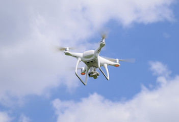 Flight quadrocopters white against the blue sky with clouds