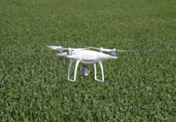 Obraz na płótnie Canvas Flying white quadrocopters over a field of wheat