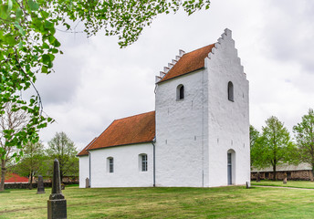 A small white medieval church with stepped gables on a green lawn
